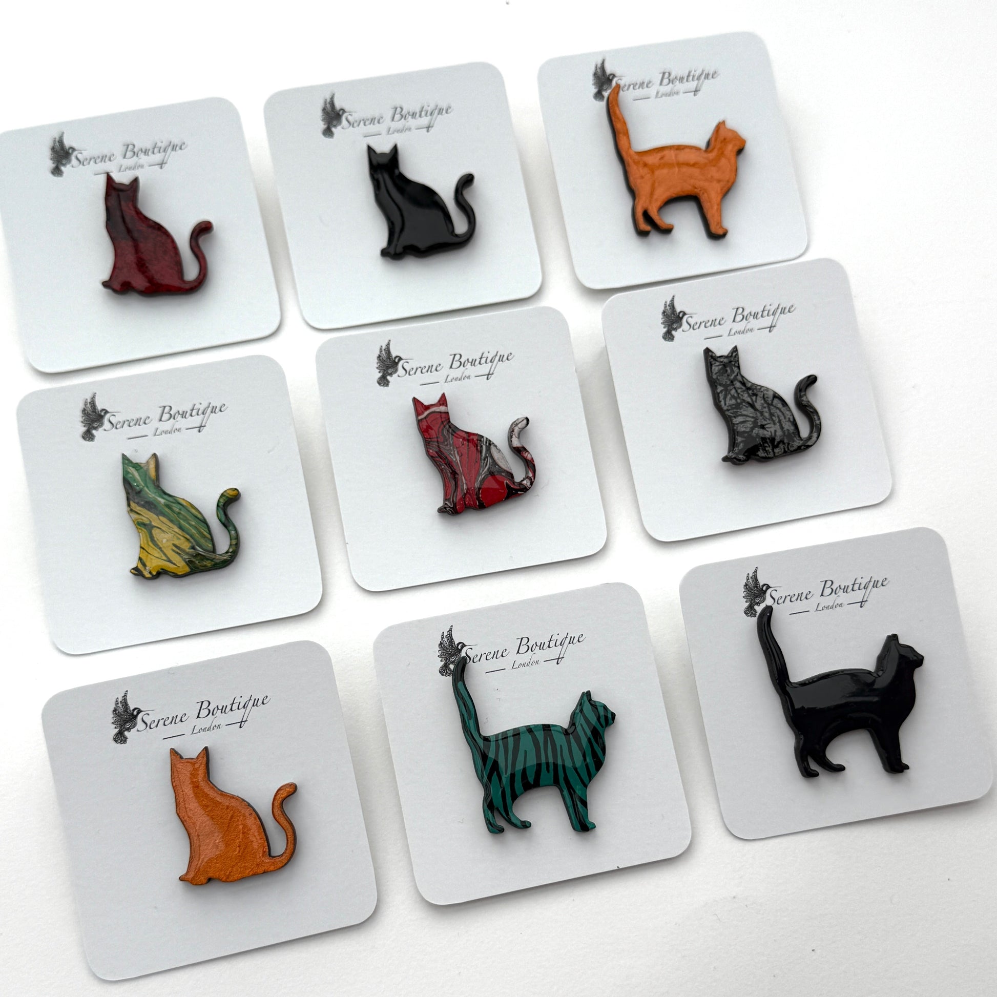 Cat-shaped pins on display cards with 'Serene Boutique' branding.